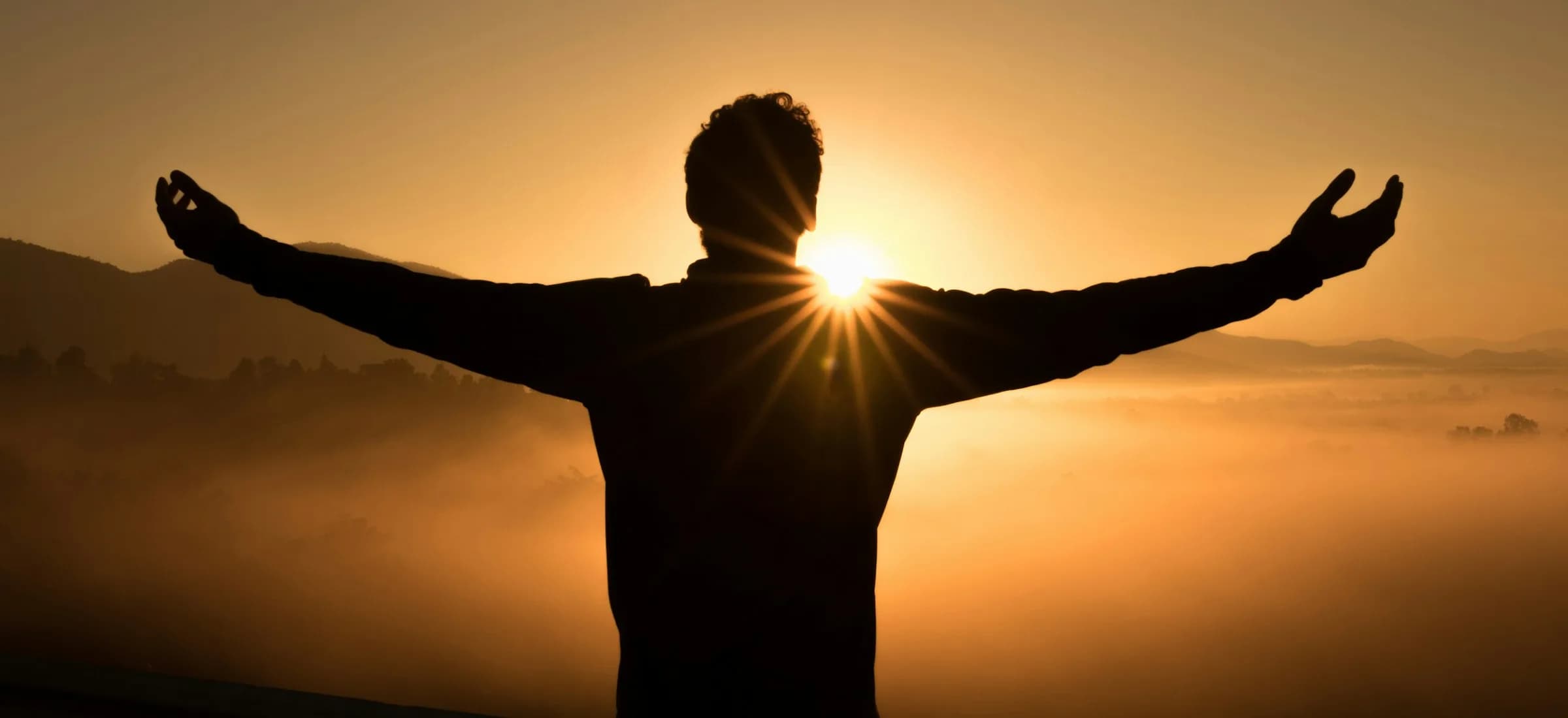 Person embracing a calm new beginning in soft sunrise light